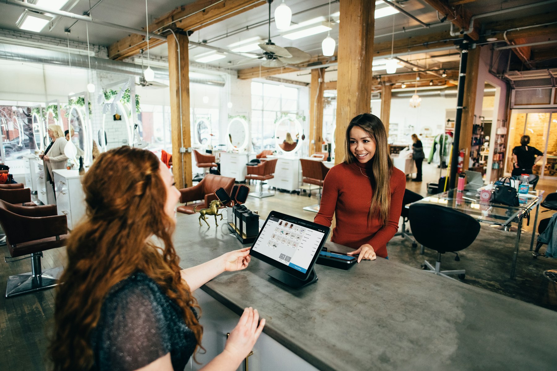 Counter staff and customer at a point-of-sale tablet — the register MiniBook3 is built for